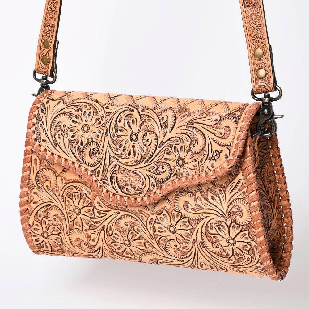 Brown leather handbag with intricate floral patterns on a white background