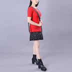 Woman wearing a red top and black skirt with a black bag on a gray background