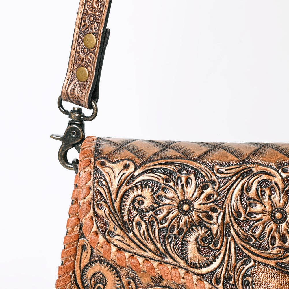 Handcrafted leather bag with intricate tooled design on a white background