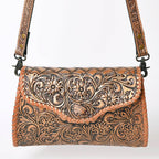 Tooled leather handbag with a decorative strap on a white background