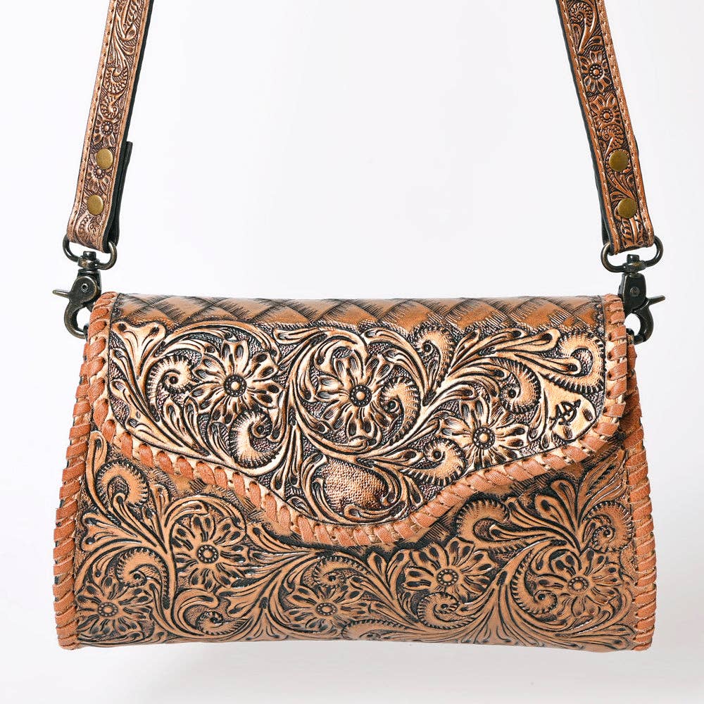 Tooled leather handbag with a decorative strap on a white background