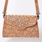 Handcrafted leather bag with intricate tooled design on a white background