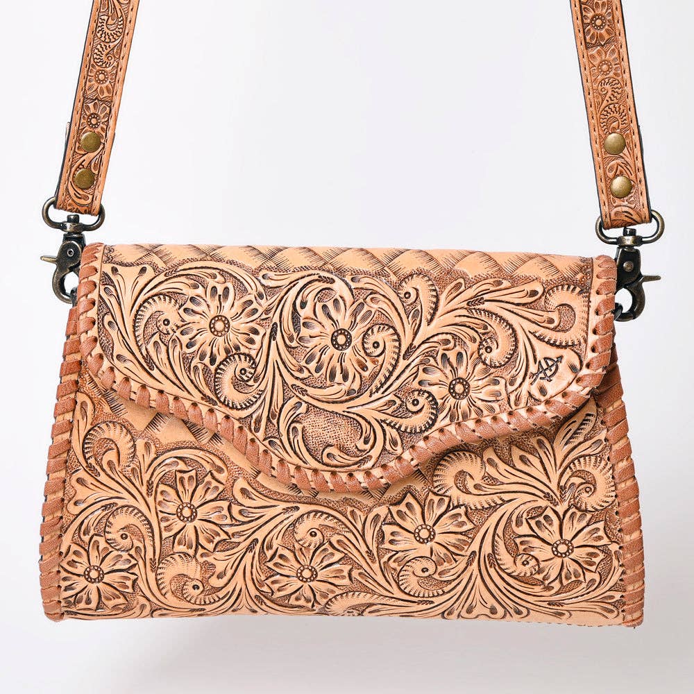 Handcrafted leather bag with intricate tooled design on a white background
