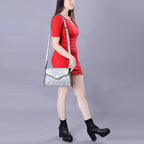Woman in a red dress holding a silver handbag against a gray background