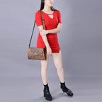 Woman in a red dress holding a brown handbag against a gray background