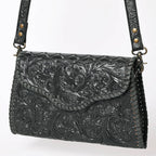 Black leather handbag with intricate floral embossing on a white background