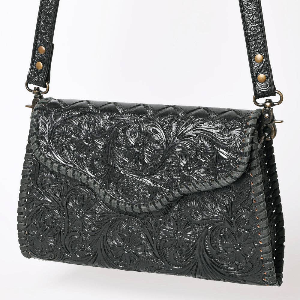 Black leather handbag with intricate floral embossing on a white background