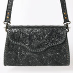 Black leather handbag with intricate floral tooled design on a white background